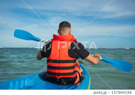 Man in kayak paddling through calm sea waters enjoying the sun 137804198