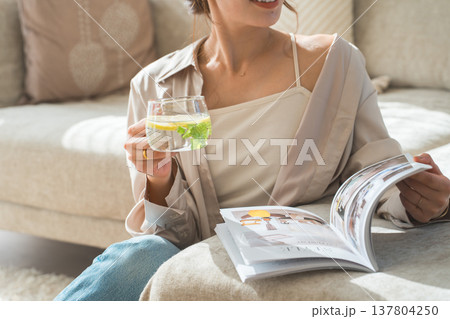 ソファーに座りレモン水,デトックスウォーターを飲む女性 ソファーに座りレモン水,デトックスウォーターを飲む女性 137804250