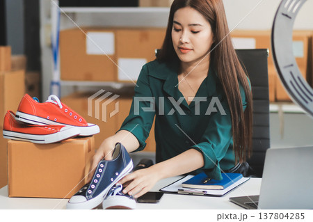 Starting small businesses SME owners female entrepreneurs check online orders to prepare to pack the boxes, sell to customers, sme business ideas online. Starting small businesses SME owners female entrepreneurs check online orders to prepare to pack the boxes, sell to customers, sme business ideas online. 137804285