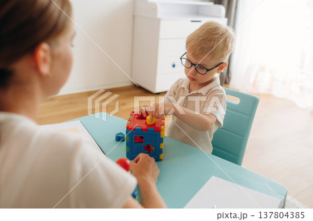 Tongue test. Speech therapist is with young boy indoors Tongue test. Speech therapist is with young boy indoors 137804385