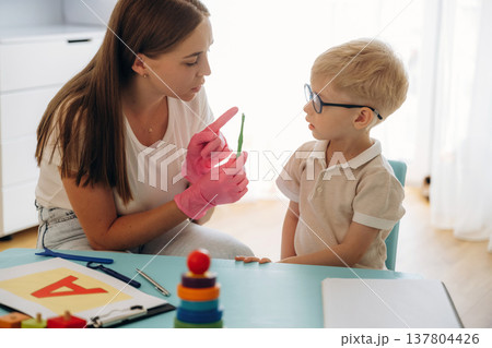 Special tests for tongue by using device. Speech therapist is with young boy indoors 137804426