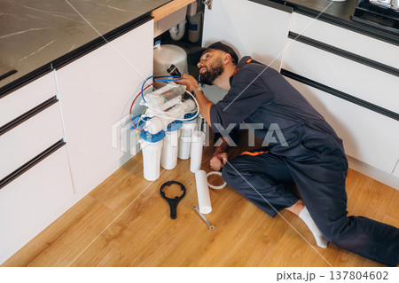 Plumber working in the kitchen under the sink Plumber working in the kitchen under the sink 137804602