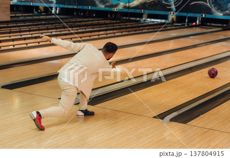 Throwing the ball. Man is playing bowling indoors Throwing the ball. Man is playing bowling indoors 137804915