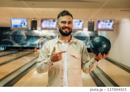 Holding the ball, standing. Man is playing bowling indoors Holding the ball, standing. Man is playing bowling indoors 137804925