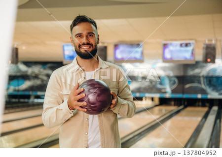 Front view, standing and holding ball. Man is playing bowling indoors Front view, standing and holding ball. Man is playing bowling indoors 137804952