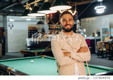 Standing and posing. Handsome man with a pool table game 137804976