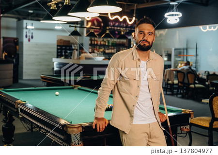 Standing and posing. Handsome man with a pool table game 137804977