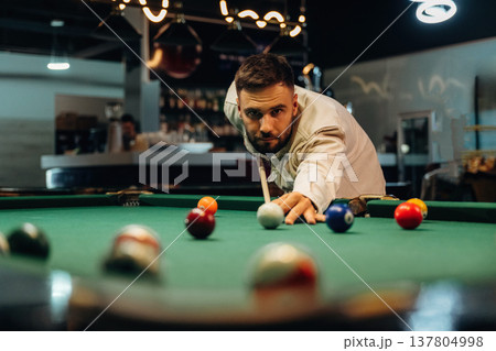 Using cue stick. Handsome man with a pool table game 137804998
