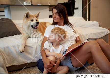 Looking at the pet. Mother with son and Shibu Inu dog are at home 137805209