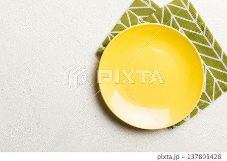 Top view on colored background empty round yellow plate on tablecloth for food. Empty dish on napkin with space for your design Top view on colored background empty round yellow plate on tablecloth for food. Empty dish on napkin with space for your design 137805428