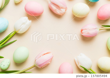Happy Easter composition. Easter eggs on colored table with yellow Tulips. Natural dyed colorful eggs background top view with copy space 137805494