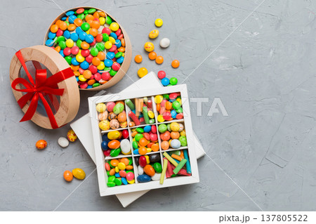 Set of different sweet candy in a paper box with a satin ribbon on a colored background. Holiday concept 137805522