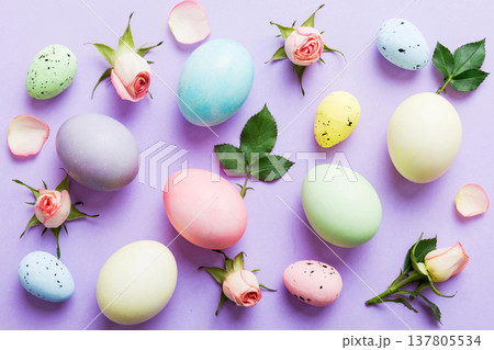 Happy Easter. Easter eggs on colored table with yellow roses. Natural dyed colorful eggs background top view with copy space Happy Easter. Easter eggs on colored table with yellow roses. Natural dyed colorful eggs background top view with copy space 137805534