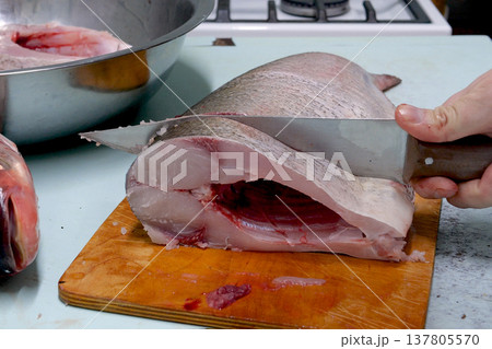 Man prepares fresh silver carp fish. Cuts it into steaks with a knife. home cooking concept 137805570