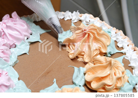 Confectioner woman is pouring cream on sponge cake using pastry bag, closeup view. Pastry chef is cooking homemade cake. cooking, baking and cooking, home cooking Confectioner woman is pouring cream on sponge cake using pastry bag, closeup view. Pastry chef is cooking homemade cake. cooking, baking and cooking, home cooking 137805585