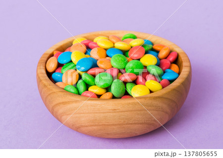 Multicolored candies in a bowl on a colored background. birthday and holiday concept. Top view with copy space Multicolored candies in a bowl on a colored background. birthday and holiday concept. Top view with copy space 137805655