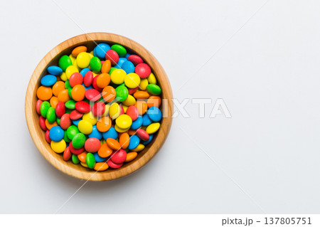 Multicolored candies in a bowl on a colored background. birthday and holiday concept. Top view with copy space 137805751