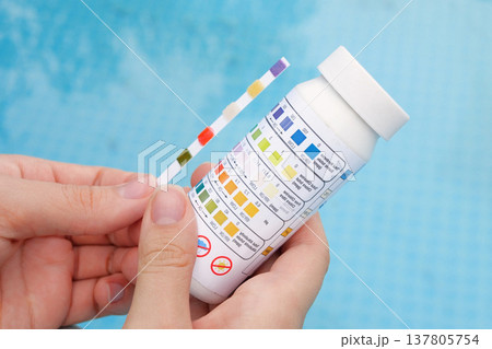 Analysis of the PH and chlorine of the water in a swimming pool in Summer. Check quality of water with test strip, comparing results Analysis of the PH and chlorine of the water in a swimming pool in Summer. Check quality of water with test strip, comparing results 137805754