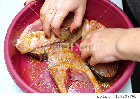 Marinated fish with spices. Before cooking, the hand of the cook smears butter and spices. home cooking concept Marinated fish with spices. Before cooking, the hand of the cook smears butter and spices. home cooking concept 137805769