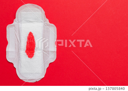 Women hygiene products or Sanitary pad with red feather on colored background. Pastel color. Closeup. Empty place for text. Female daily hygiene 137805840
