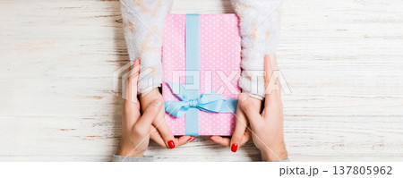Top view of a man and a woman giving and receiving gift for a holiday on wooden background. Close up of love and relationship concept Top view of a man and a woman giving and receiving gift for a holiday on wooden background. Close up of love and relationship concept 137805962