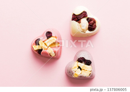 chocolate sweets in the form of a heart with fruits and nuts on a colored background. top view with space for text, holiday concept chocolate sweets in the form of a heart with fruits and nuts on a colored background. top view with space for text, holiday concept 137806005
