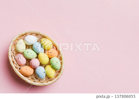 Colorful Easter eggs in wicker basket against colored background, closeup. top view with copy space 137806055