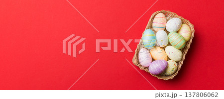 Colorful Easter eggs in wicker basket against colored background, closeup. top view with copy space Colorful Easter eggs in wicker basket against colored background, closeup. top view with copy space 137806062