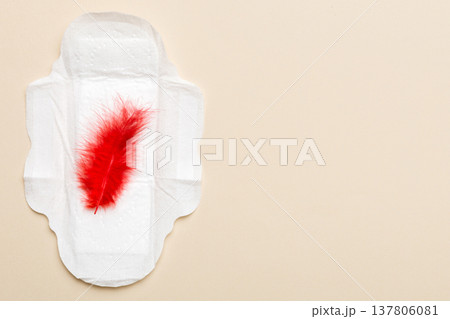Women hygiene products or Sanitary pad with red feather on colored background. Pastel color. Closeup. Empty place for text. Female daily hygiene 137806081