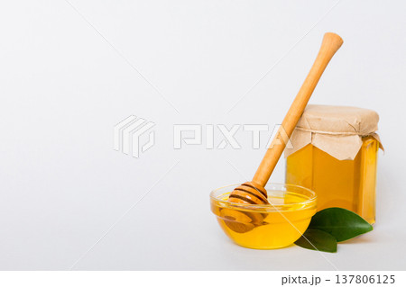 Honey in jar with leaves and honey dipper on colored background top view with copy text Honey in jar with leaves and honey dipper on colored background top view with copy text 137806125