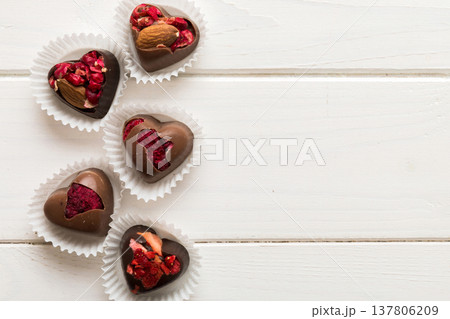 chocolate sweets in the form of a heart with fruits and nuts on a colored background. top view with space for text, holiday concept 137806209