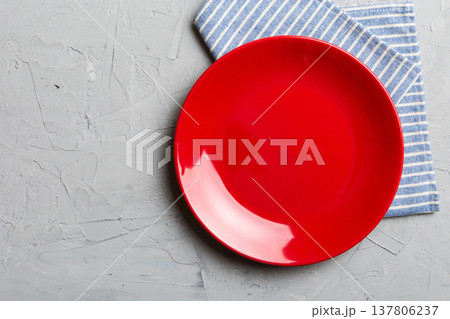 Top view on colored background empty round red plate on tablecloth for food. Empty dish on napkin with space for your design Top view on colored background empty round red plate on tablecloth for food. Empty dish on napkin with space for your design 137806237