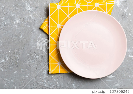 Top view on colored background empty round pink plate on tablecloth for food. Empty dish on napkin with space for your design Top view on colored background empty round pink plate on tablecloth for food. Empty dish on napkin with space for your design 137806243