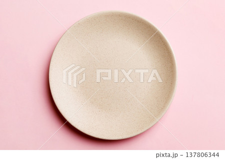 Top view of isolated of colored background empty round beige plate for food. Empty dish with space for your design 137806344