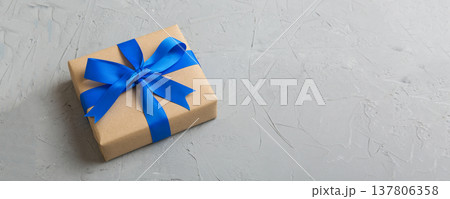 Wrapped christmas or other holiday handmade present in craft paper with colored ribbon. Present box, decoration of gift on table, top view with copy space Wrapped christmas or other holiday handmade present in craft paper with colored ribbon. Present box, decoration of gift on table, top view with copy space 137806358