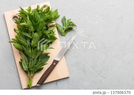 Bunch of fresh mint on the cutting boards, colored background top view Bunch of fresh mint on the cutting boards, colored background top view 137806370