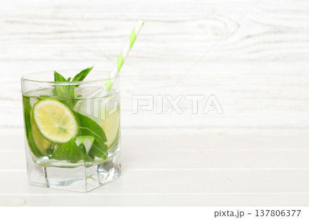 Mojito cocktail. Refreshing mojito cocktail with lime, lemon and mint in a tall glass with a stick Mojito cocktail. Refreshing mojito cocktail with lime, lemon and mint in a tall glass with a stick 137806377