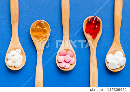 Vitamin capsules in a spoon on a colored background. Pills served as a healthy meal. Red soft gel vitamin supplement capsules on spoon Vitamin capsules in a spoon on a colored background. Pills served as a healthy meal. Red soft gel vitamin supplement capsules on spoon 137806452