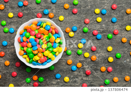 Multicolored candies in a bowl on a colored background. birthday and holiday concept. Top view with copy space Multicolored candies in a bowl on a colored background. birthday and holiday concept. Top view with copy space 137806474
