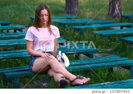 Lonely sad young woman sits on bench in ummer park 137807403