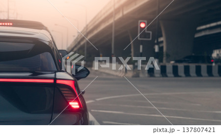 Rear side of luxury cars stop in the road intersection. By traffic red light control under overpass. Warm atmosphere of the evening sky. Rear side of luxury cars stop in the road intersection. By traffic red light control under overpass. Warm atmosphere of the evening sky. 137807421