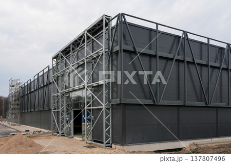 Modern Industrial Warehouse Under Construction with Steel Frame and Dark Metal Facade Exterior Modern Industrial Warehouse Under Construction with Steel Frame and Dark Metal Facade Exterior 137807496