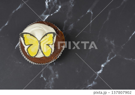 Top View of Chocolate Cupcake with Yellow Butterfly on Dark Marble Top View of Chocolate Cupcake with Yellow Butterfly on Dark Marble 137807902