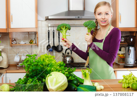 Woman in kitchen with green vegetables broccoli in hand 137808117