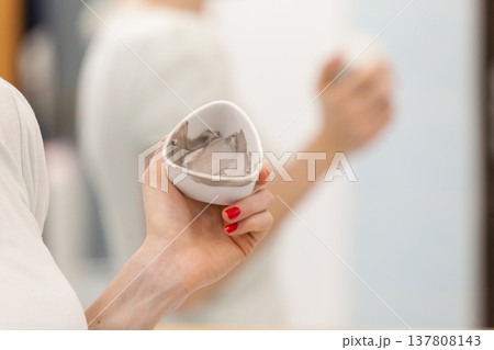 Female hand holding bowl with clay mud mask. Skin care. Female hand holding bowl with clay mud mask. Skin care. 137808143