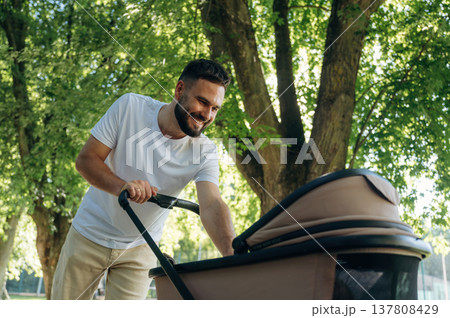 Very happy, parenting conception. Father is with cradle, having a walk in the park Very happy, parenting conception. Father is with cradle, having a walk in the park 137808429
