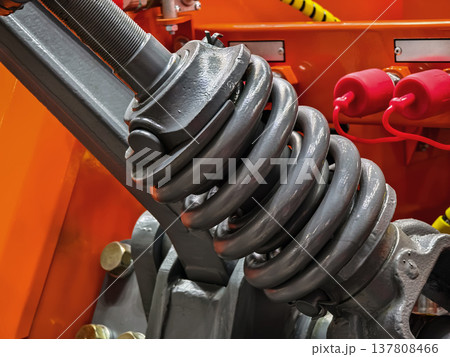 Close view of a coil spring and mechanical parts on heavy equipment in a workshop setting Close view of a coil spring and mechanical parts on heavy equipment in a workshop setting 137808466