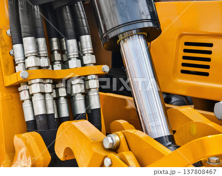Details of hydraulic system on yellow construction equipment with focus on hoses and fittings during day 137808467