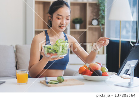 Fit young Asian women in activewear sitting on yoga mat and eating fresh vegetable salad after workout, representing clean eating, fitness lifestyle, wellness routine and health balance. Fit young Asian women in activewear sitting on yoga mat and eating fresh vegetable salad after workout, representing clean eating, fitness lifestyle, wellness routine and health balance. 137808564