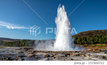 空高く噴き出す間欠泉のダイナミックな光景。青空と湯気、広い余白のある背景素材。 137808722